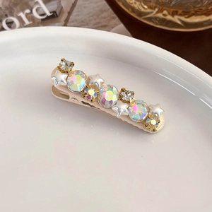 Close-up of pink star hair clip with pearls and AB rhinestones on a ceramic dish