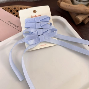 Detail of light blue ribbon bow hair clips set on a white decorative display tray