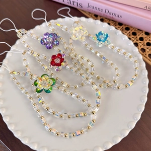 Close-up of colorful crystal flower phone straps with faceted glass beads on a white tray