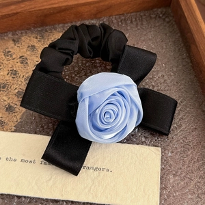 Dettaglio della elegante rosa in raso blu e fiocco in nastro nero sull'elastico