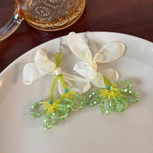 Detail of floral gauze earrings with cream ribbon bows and colorful crystal beads