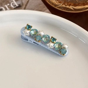 Detailed macro view of light blue hair clip with stars and crystals on white plate