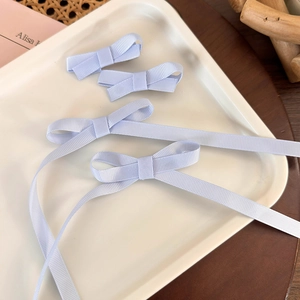 Detail of light purple grosgrain ribbon bow hair clips set with long elegant streamers