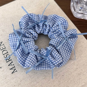 Detailed blue plaid scrunchie with delicate light blue ribbon bow accents and fabric texture
