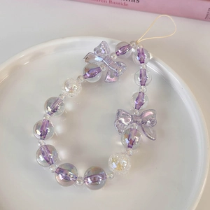 Detail of purple translucent beaded phone strap with iridescent bow in a ceramic tray