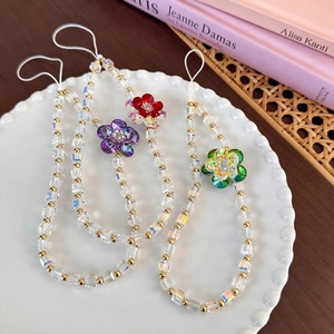 Detail of handmade floral beaded phone charms with crystal cubes and gold beads on a plate