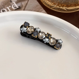 Detailed shot of star-shaped rhinestones and champagne crystals on a black hair clip