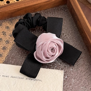 Dettaglio dell'elastico per capelli nero con rosa in raso e fiocco setoso elegante