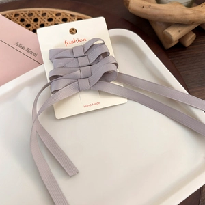 Detailed set of four lavender ribbon bow hair clips displayed on a professional white card