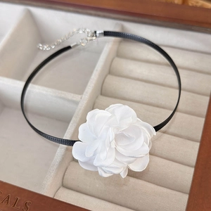 Close-up of elegant handmade white fabric rose choker with black satin ribbon and clasp