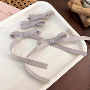 Detail of 4-piece gray ribbon bow hair clips set on an elegant white display tray