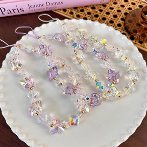 Colorful butterfly phone charm with iridescent beads and gold accents on a white tray