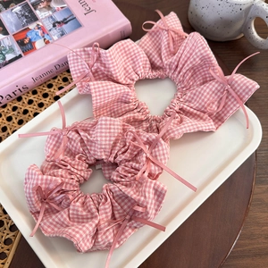 Pink checkered scrunchies with bow ribbons in a stylish French lifestyle setup