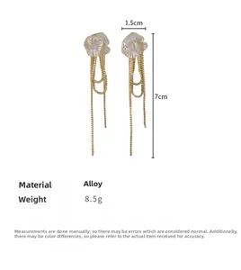 Vue détaillée des boucles d'oreilles camélia à pompons, dimensions 1,5 cm par 7 cm