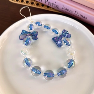 Detail of blue beaded phone strap with translucent bow beads on a white ceramic plate