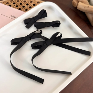 Detail view of black grosgrain ribbon bow hair clips with long streamers in a set
