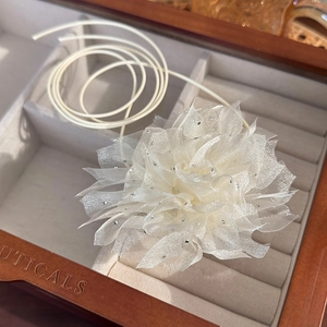 Detailed view of a cream fabric 3D flower choker with rhinestones in a wooden jewelry box