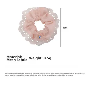 Pink mesh scrunchie with lace edge, bow, and heart rhinestone detail measuring 14cm