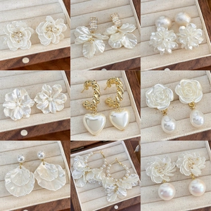 Dettaglio di nove paia di orecchini eleganti con fiori e perle dorate in una scatola