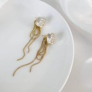 Détail de boucles d'oreilles camélia à franges avec pétales blancs et chaînes dorées