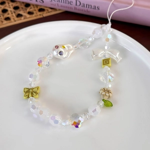 Détail d'une dragonne en perles colorées avec breloques papillon et perle fantôme sur plateau