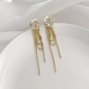 Détail de boucles d'oreilles camélia avec chaînes box dorées et pétales blancs