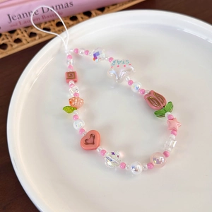 Détail d'un bijou de téléphone perlé avec cœurs roses, étoiles et tulipes en plat