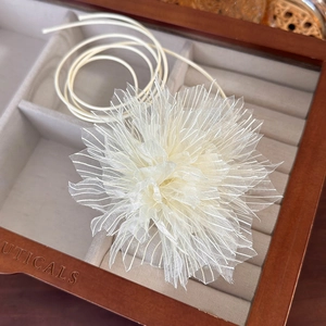 Detail of elegant beige organza flower necklace with delicate layers and long ribbons