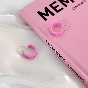 Detail showing the pink C-shape twisted hoop earrings with woven texture on silk fabric