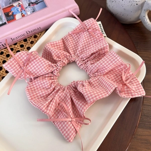Detailed view of pink plaid scrunchie with silk bows on a white decorative tray