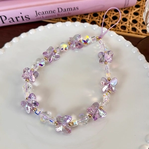 Detailed macro of iridescent purple butterfly beads and faceted gems on phone strap