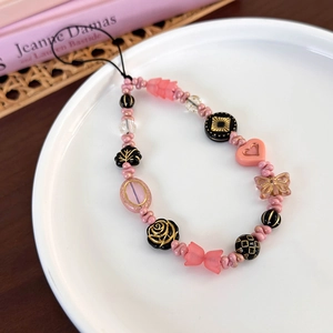 Détail de la chaîne de téléphone avec perles cœurs roses et breloques papillon