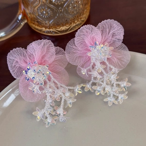 Detail of pink mesh flower earring with crystal beads on a minimalist grey plate