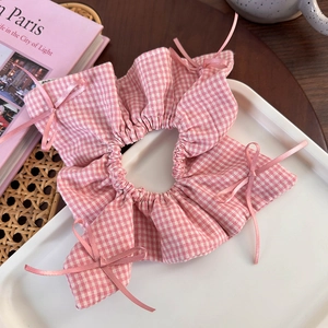 Detailed macro view of pink gingham scrunchie with delicate silk bow embellishments