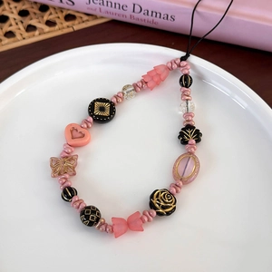Détail de la lanière de téléphone en perles roses avec papillon et fleurs roses