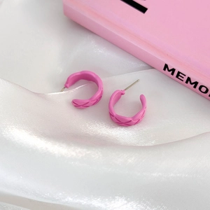 Pink C-shape hoop earrings with quilted pattern on white silk fabric background