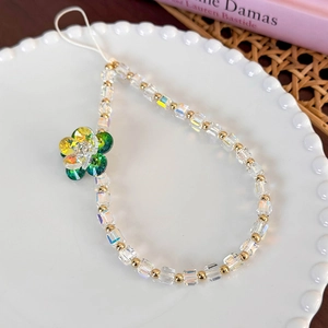 Detail of colorful glass bead phone strap with a green crystal flower on a white plate