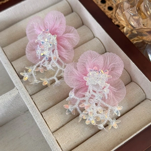 Close-up of pink tulle flower earrings with white beads and petals in a jewelry box