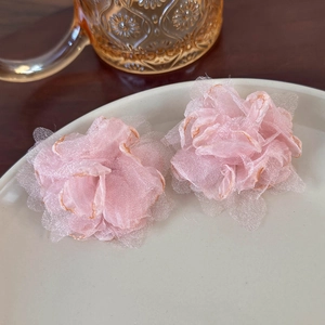 Detail of pink mesh flower earrings with gold trim on an elegant cream porcelain plate