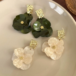 Detail of floral acrylic earrings in forest green and cream white with gold hammered metal