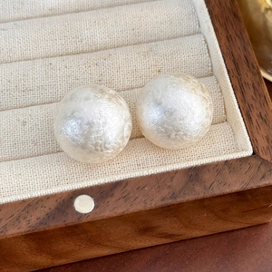 Dettaglio di grandi orecchini di perle bianche con trama perlata in scatola di legno