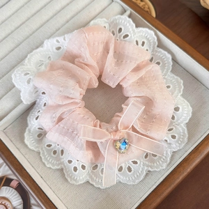 Detail of pink lace scrunchie with bow and heart rhinestone on a display tray