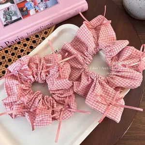 Pink checkered scrunchies with delicate ribbon bows on a white tray set for women