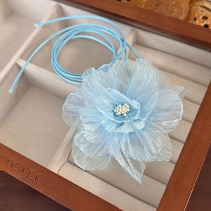 Close-up of handmade sky blue fabric flower choker with white beaded stamens