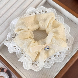 Close-up of pale yellow lace scrunchie with silk bow and sparkling rhinestone detail
