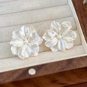 Dettaglio di orecchini a camelia bianca con lucentezza perlata in portagioie di legno