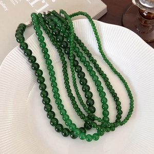 Elegant emerald green beaded necklace with silver clasp on white ceramic tray