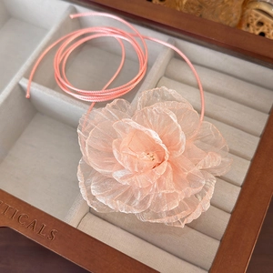 Detail of peach tulle fabric flower choker with long ribbon in wooden jewelry box