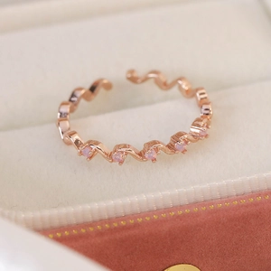 Macro shot of rose gold zigzag wavy ring with pink zircon accents in velvet jewelry box