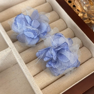 Macro shot of light blue mesh floral earrings on a velvet jewelry display box